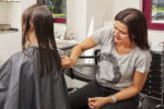 Eine Frisörmeisterin kämmt die gewaschenen Haare einer Kundin im Frisörsalon.