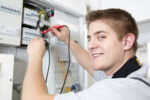 Elektriker der im Schaltkasten die Anschlüsse überprüft.